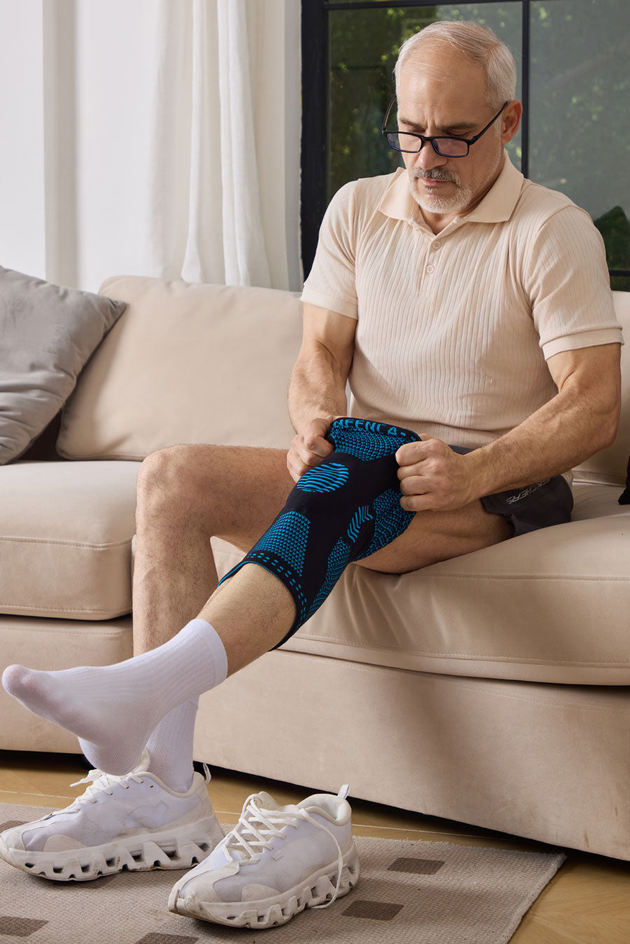 Senior man adjusting his NEENCA compression knee brace while seated at home.