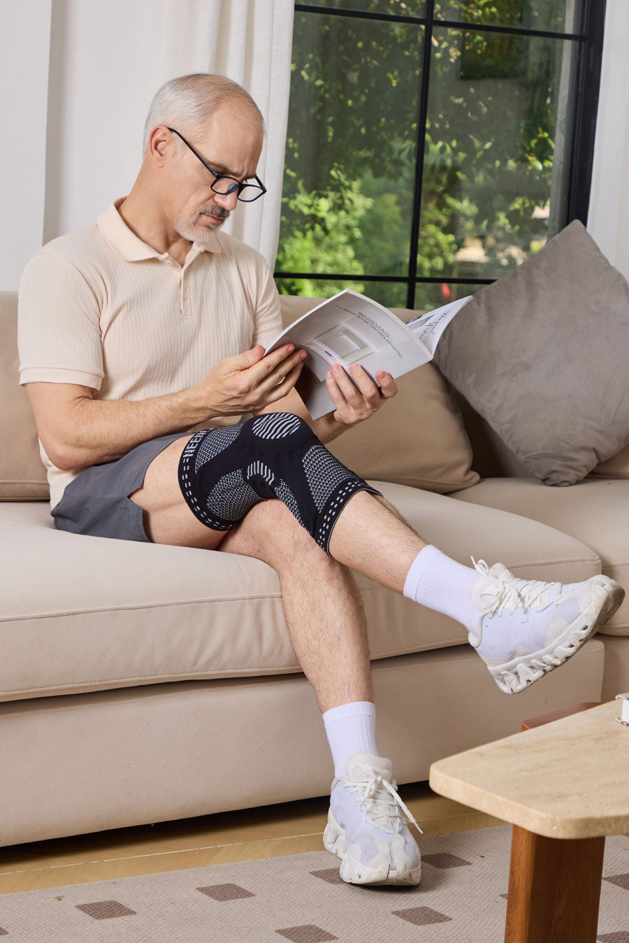 Senior man reading product instructions while wearing a NEENCA knee brace at home.