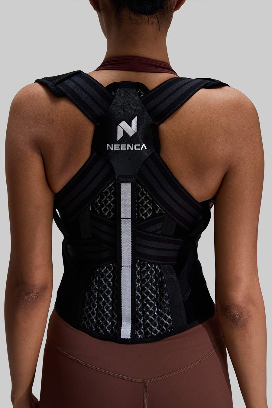 Person wearing a black Neenca back support brace on a gray background