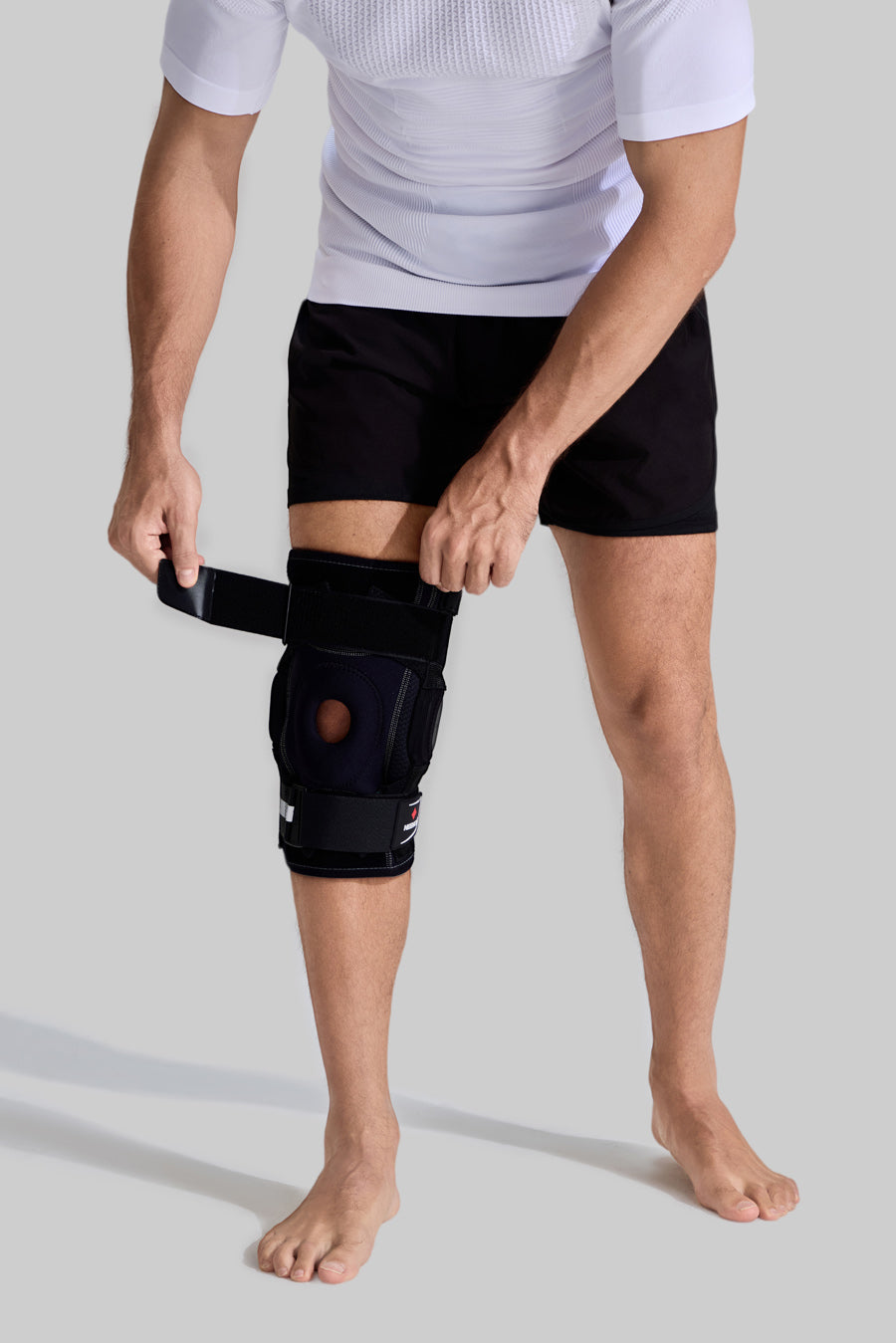 Male model wearing HX042/HX035 professional knee brace, front view showing the adjustment of compression straps