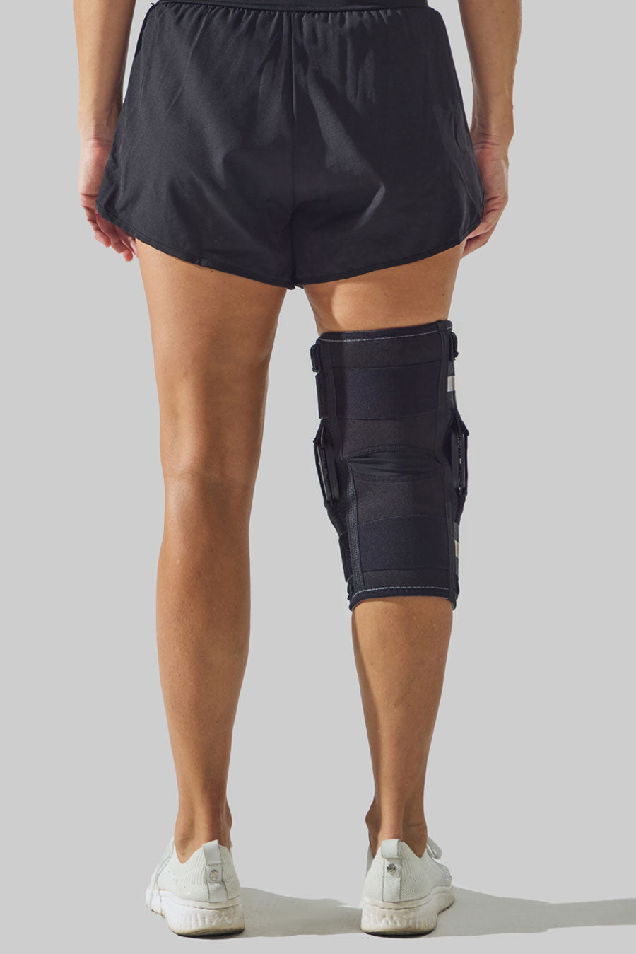 Rear view of a NEENCA hinged knee brace fitted around the knee.