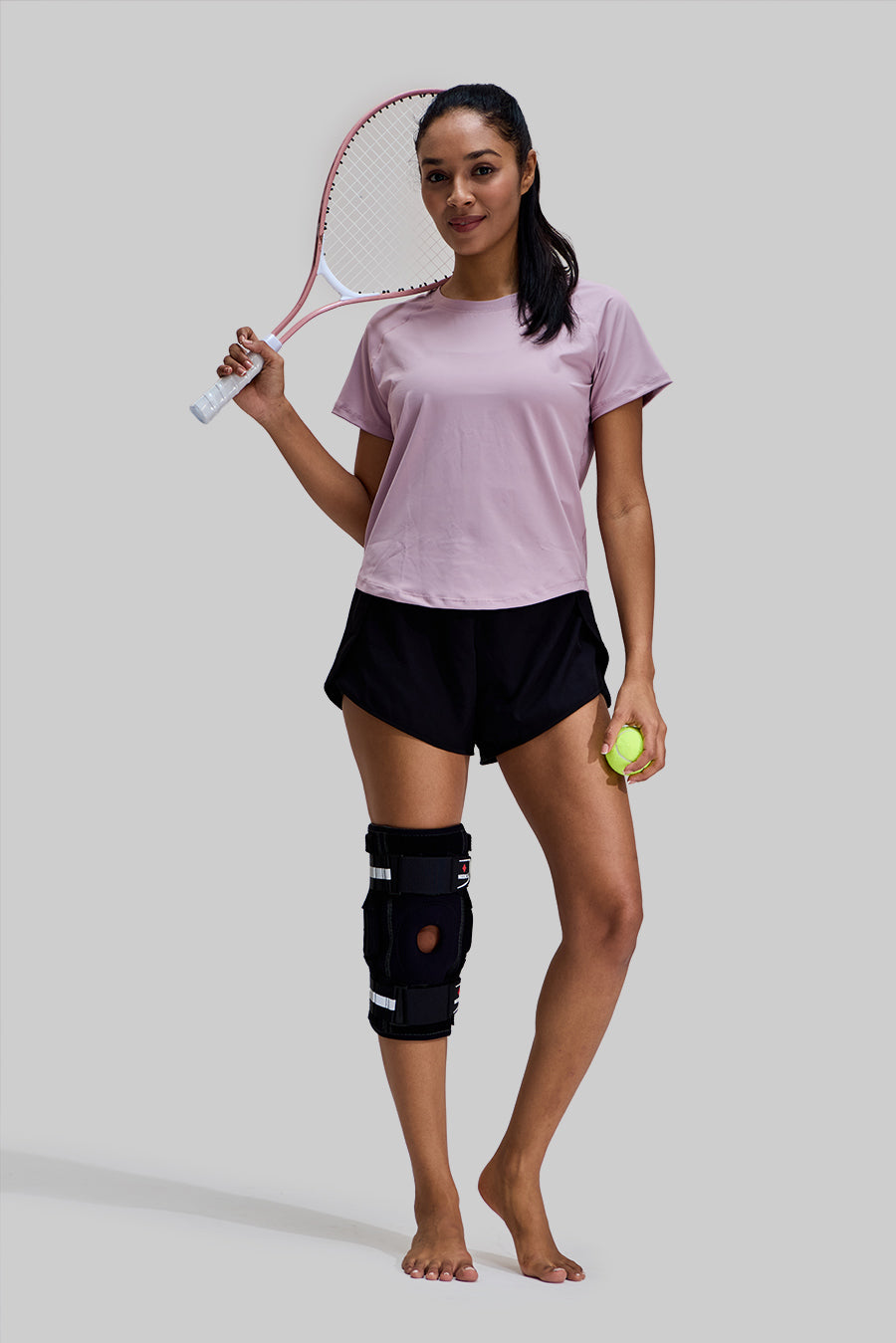 Full body view of a female tennis player wearing the NEENCA HX042/HX035 Hinged Knee Brace, demonstrating sports protection during athletic activity