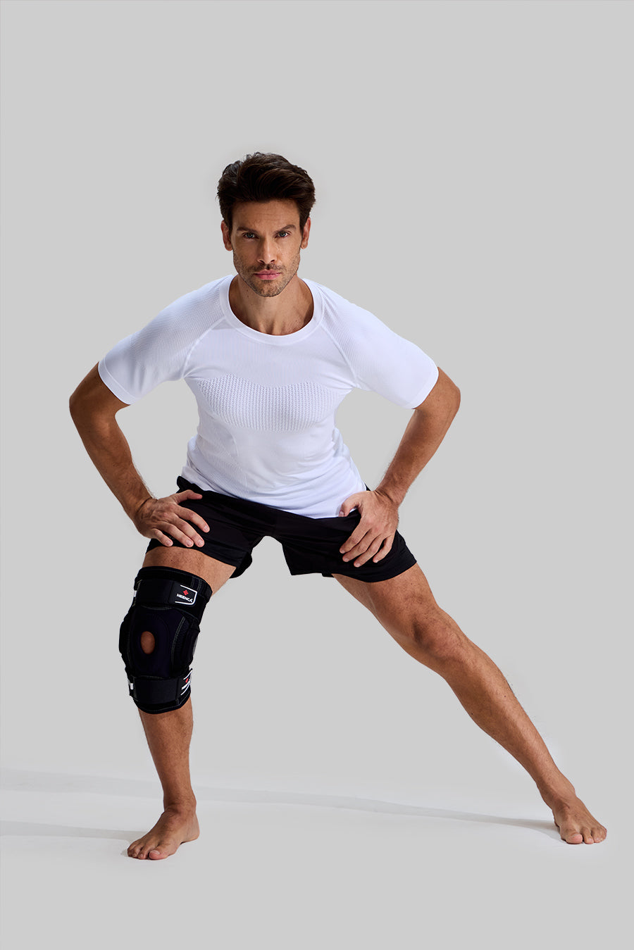 Male model performing side lunges wearing NEENCA HX042/HX035 professional knee brace for athletic support and stability