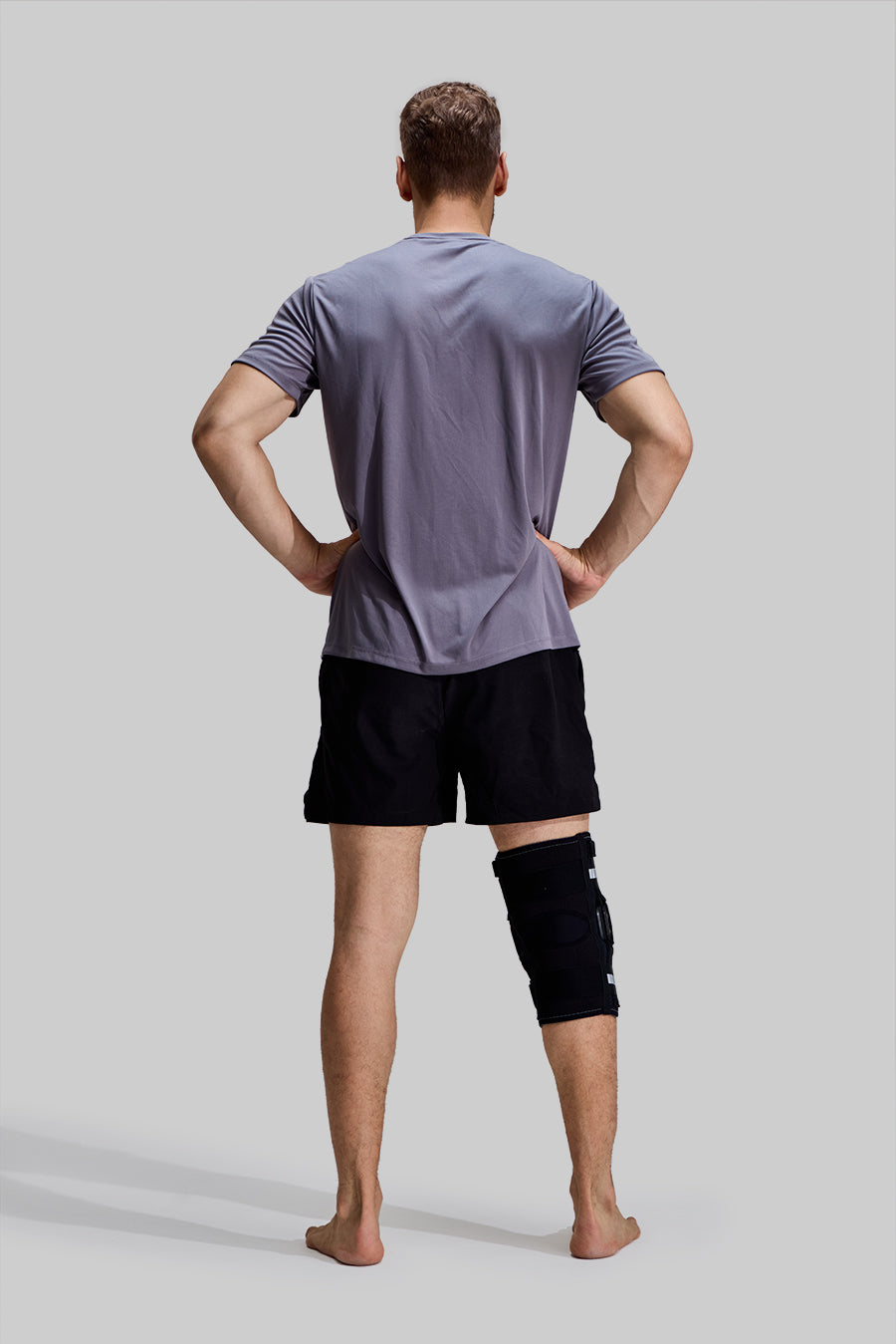 Rear view of male model wearing NEENCA HX043 professional hinged knee brace, showing back leg coverage and non-slip design