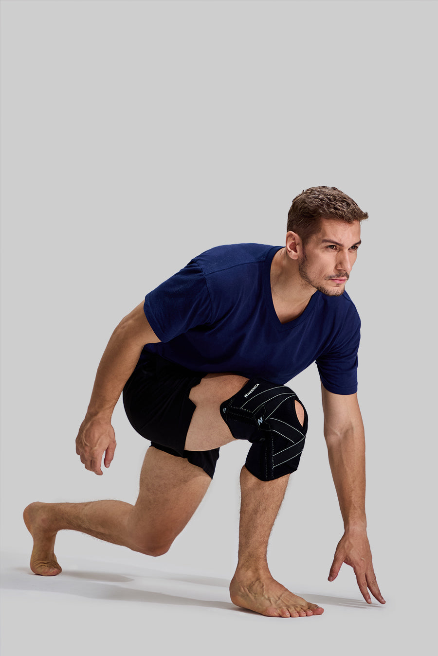 Side view of male model in a starting sprint position wearing black NEENCA HX024 professional knee brace