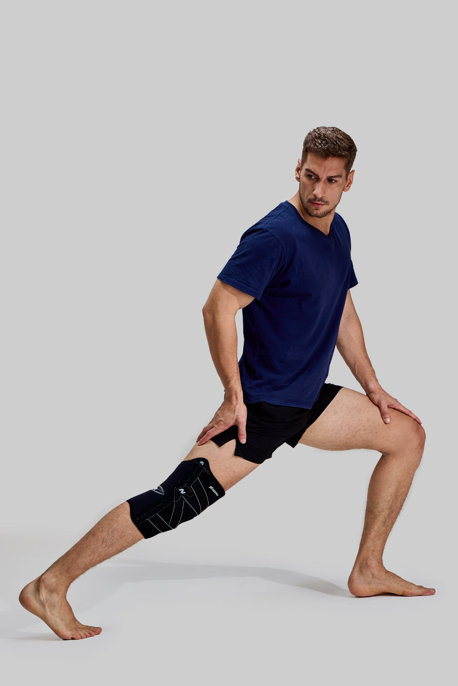 Side view of male model in deep side lunge stretching his adductors wearing black NEENCA HX024 knee brace