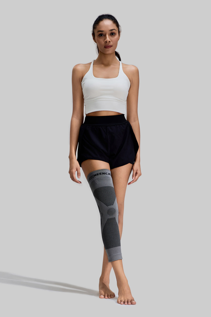 Front view of a female model wearing a grey NEENCA HX036 compression leg sleeve on her right leg