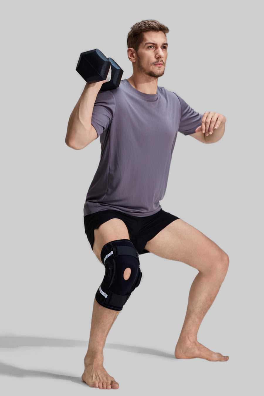 Male athlete performing dumbbell squats wearing NEENCA HX043 professional hinged knee brace for heavy-duty support and joint stability