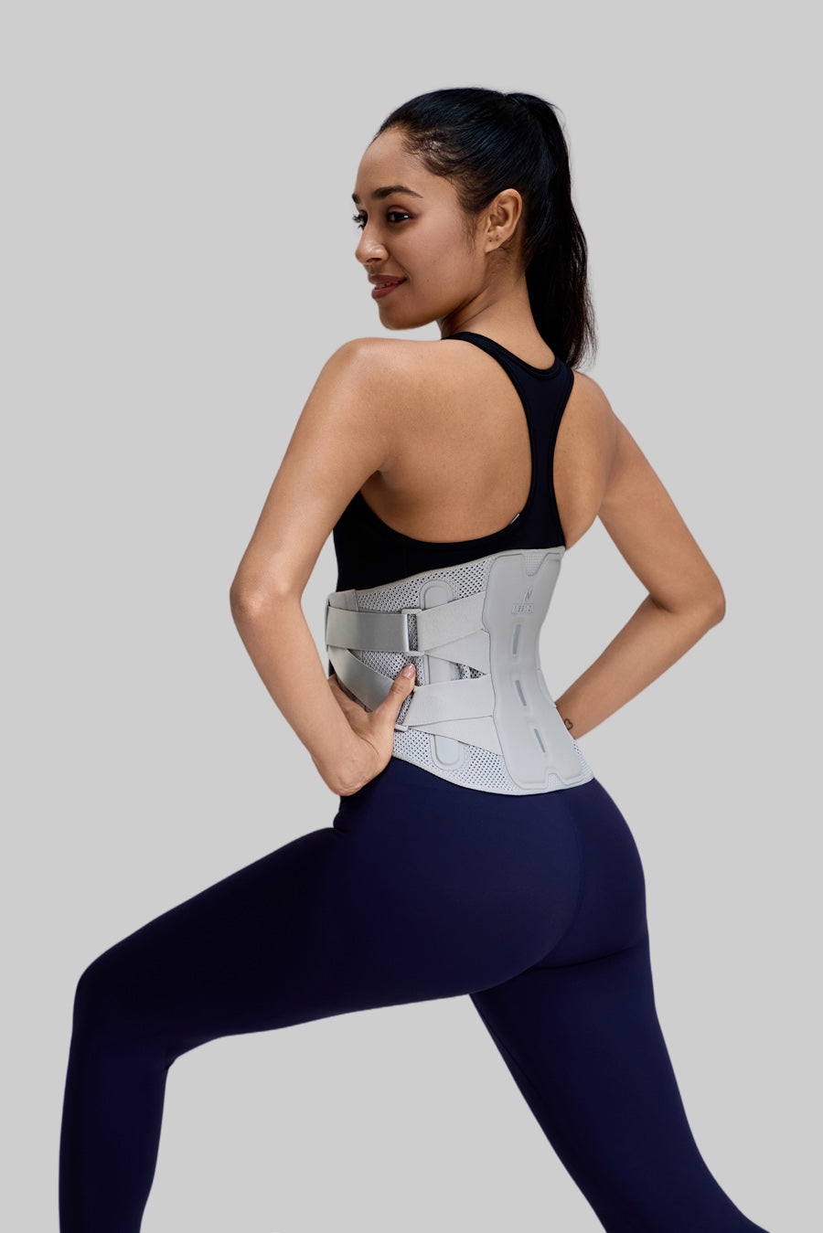 Side view of a female model in a lunge pose wearing the NEENCA HY008 back brace, showcasing the ergonomic lumbar support and pulley strap system