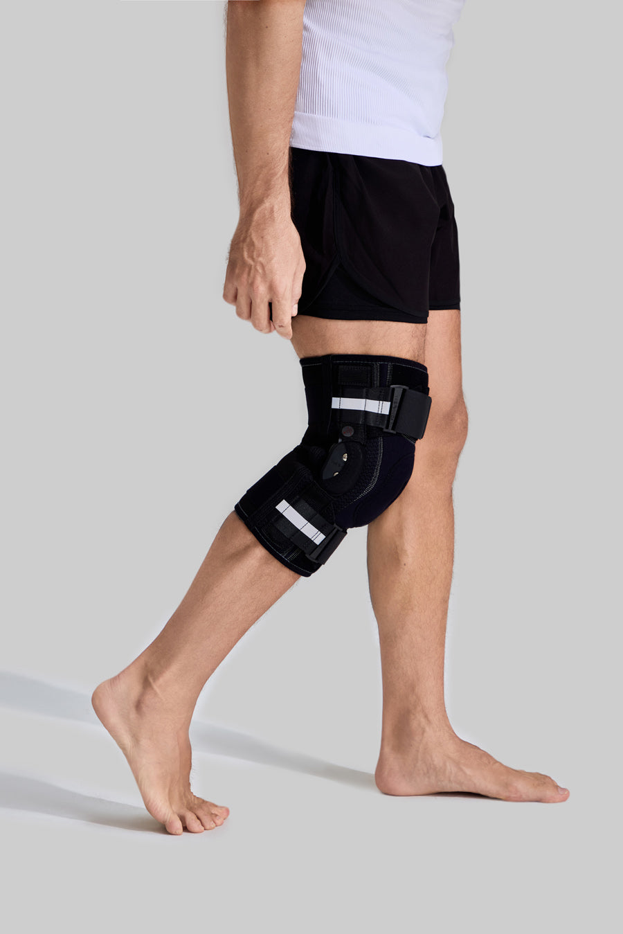 Side view of male model wearing NEENCA HX042/HX035 professional knee brace with side stabilizers and reflective straps
