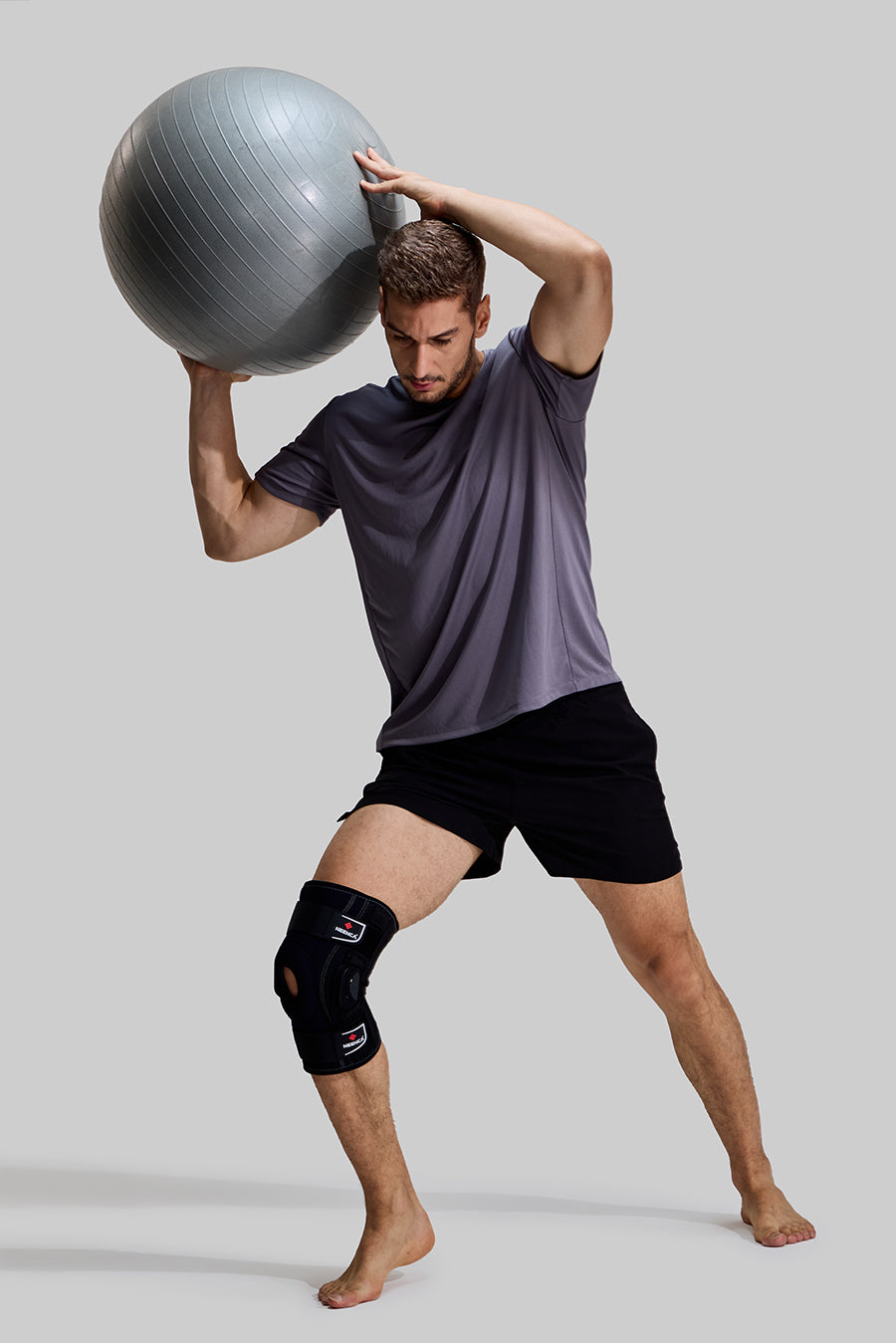 Male model using a fitness ball wearing NEENCA HX043 professional hinged knee brace, demonstrating stability during core training