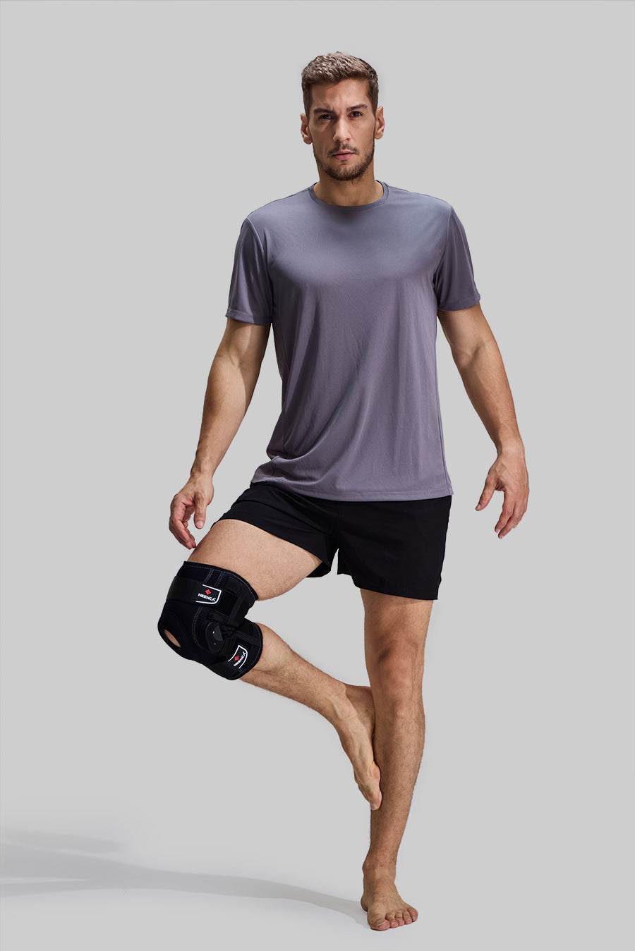 Male model balancing on one leg wearing NEENCA HX043 professional hinged knee brace, demonstrating joint stability and comfort